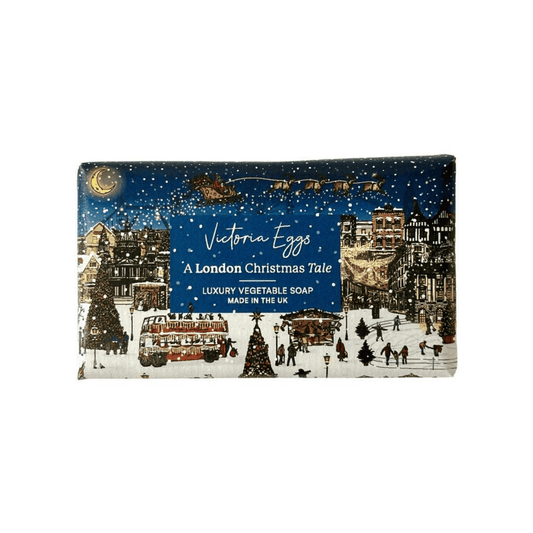 Victoria Eggs 'A London Christmas Tale' luxury vegetable soap bar, featuring a festive winter scene illustration with a blue sky, snow, red double-decker buses, and Christmas trees.