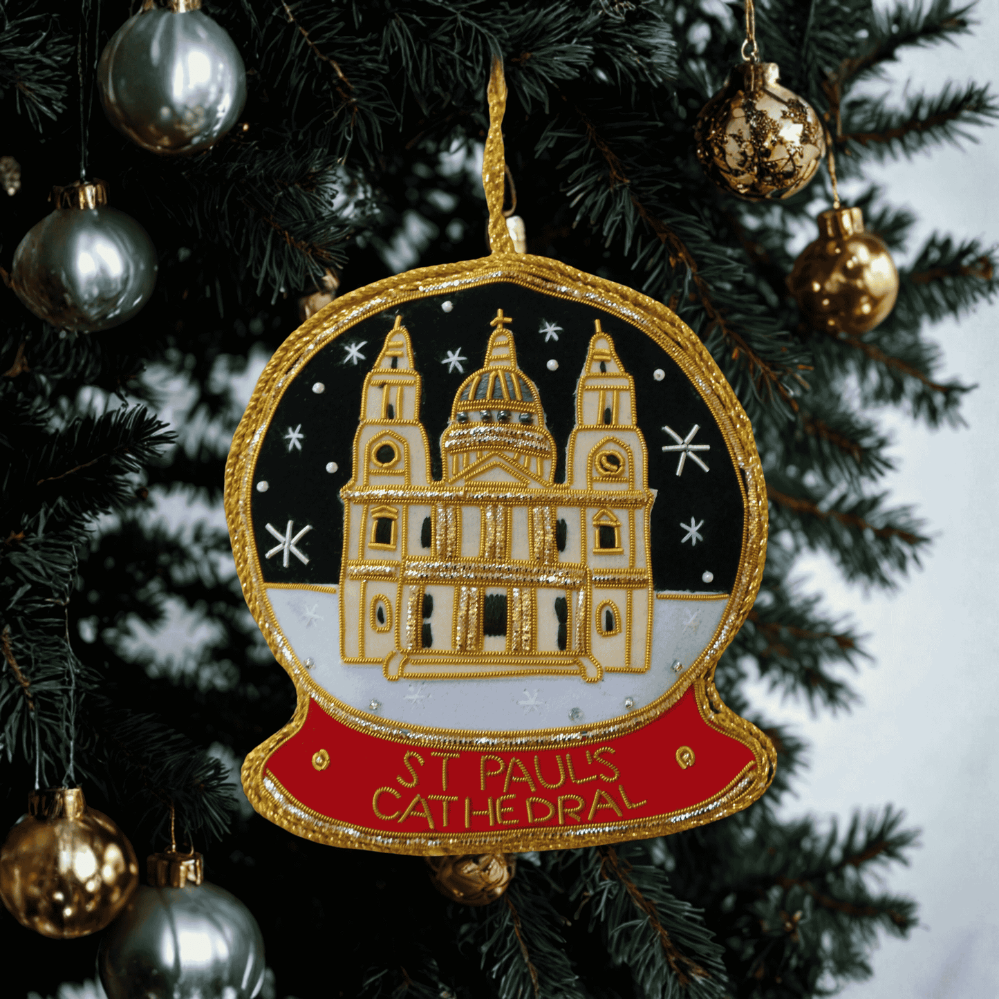 Decorative ornament of St. Paul's Cathedral on a Christmas tree with gold and silver ornaments.